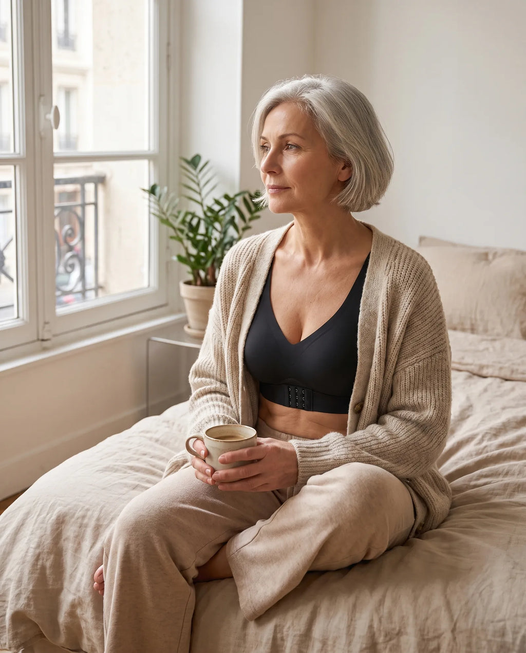 Femme de 55 ans le matin chez elle en soutien-gorge sans armature noir sous un gilet